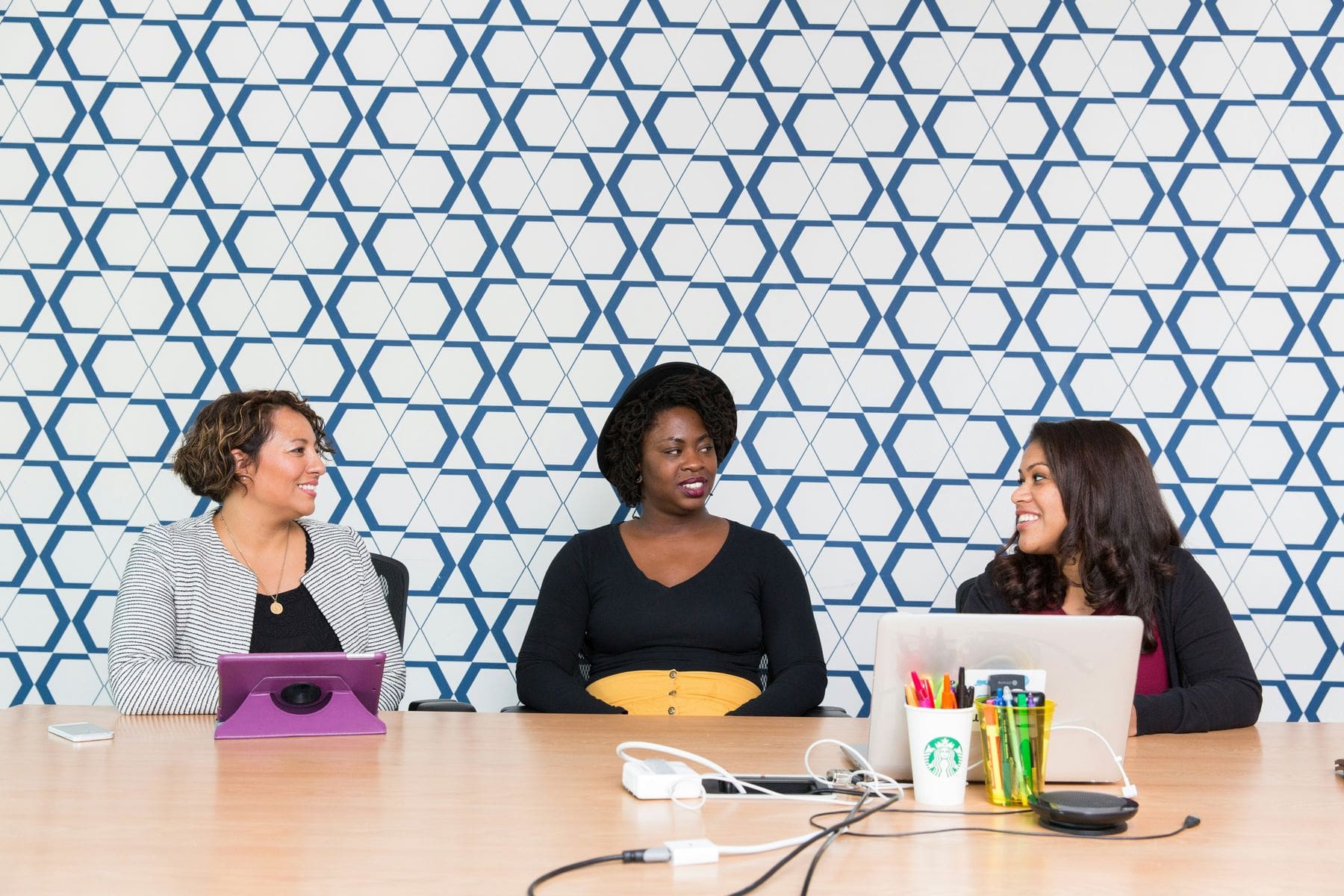 Three women sitting on a table waiting for a panel interview to start