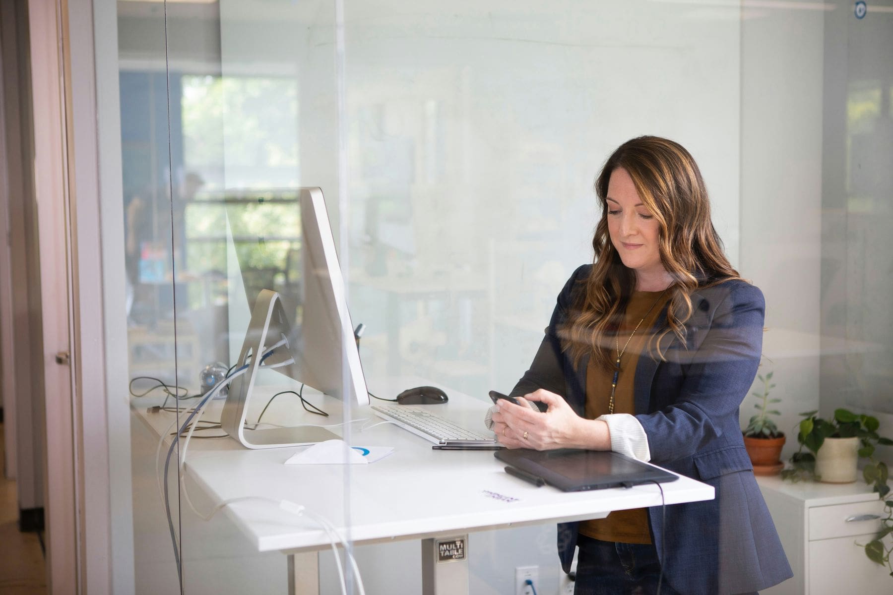 Woman looking at her phone while standing at her desk