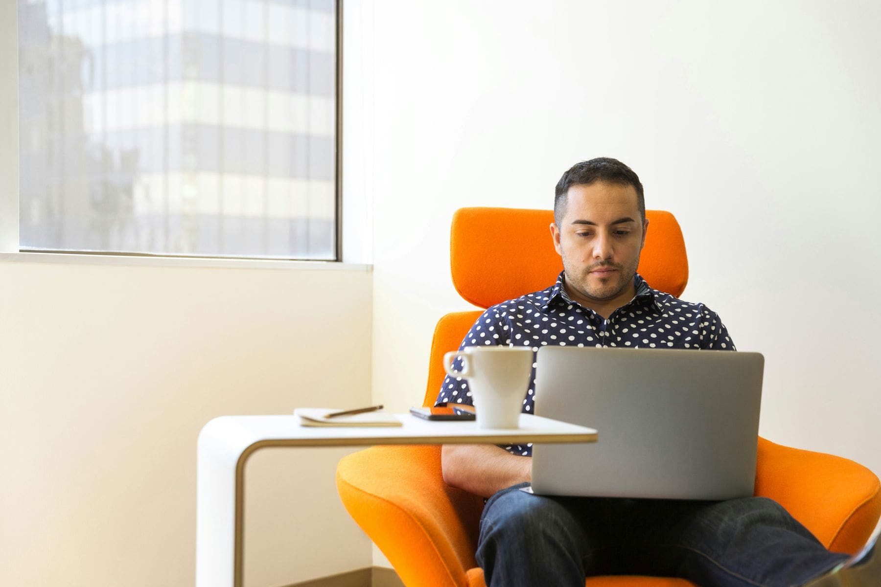 Man seating on a chair while using his laptop