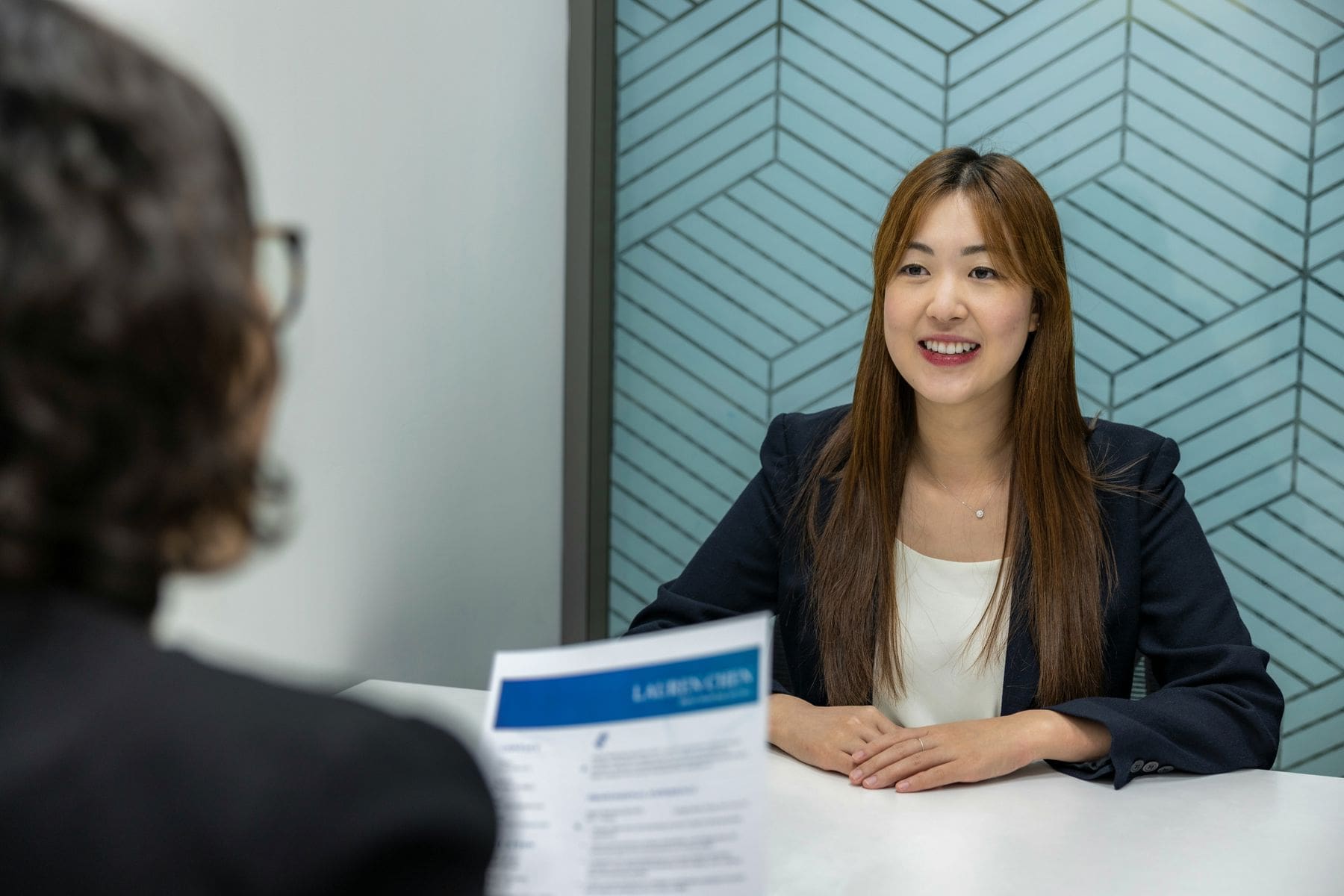 Woman looking at her interviewer as she reviews her resume during an interview