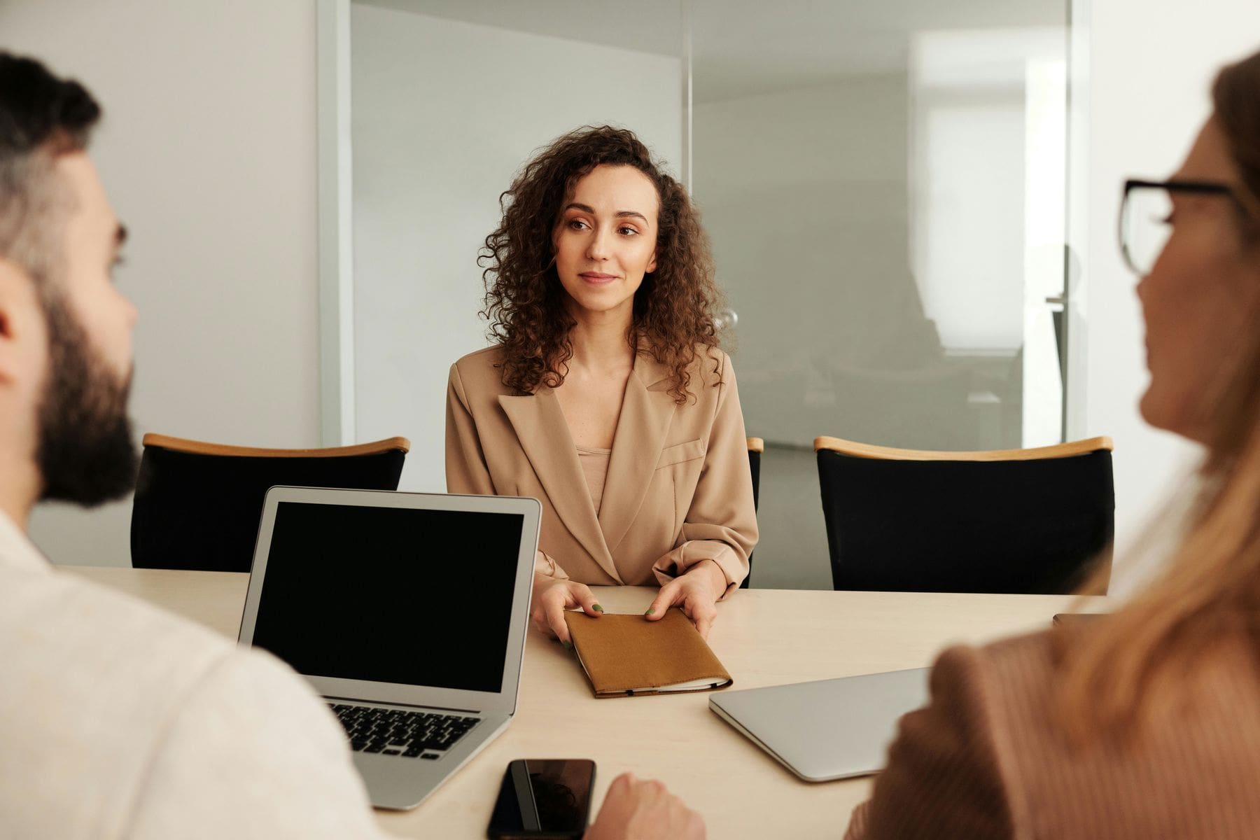 Woman holding at her notebook while looking at one of her interviewer during a job interview