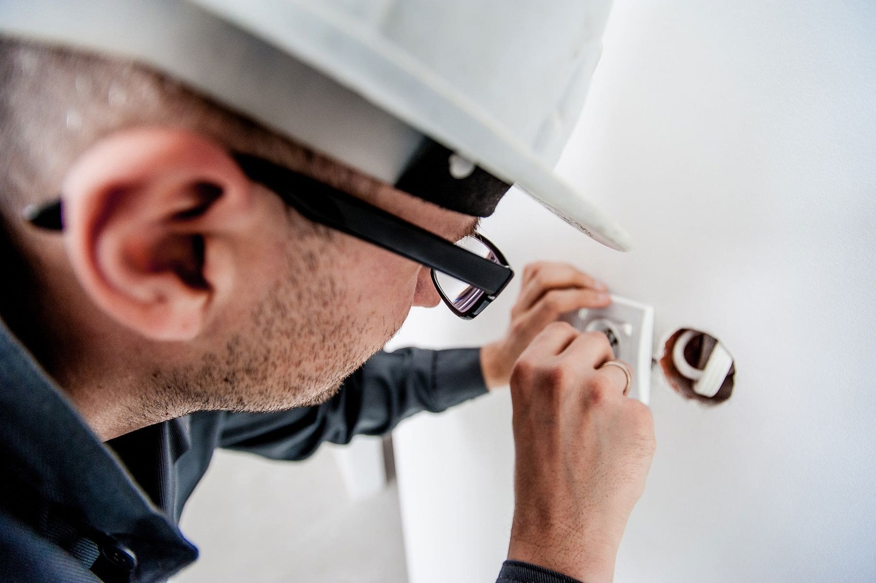 Man wearing protective helmet while fixing a socket